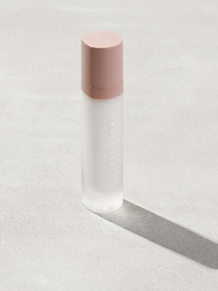 Pro Filt'r Mattifying Primer standing on a concrete-like background. The clear container showcases the primer with a pink cap.
