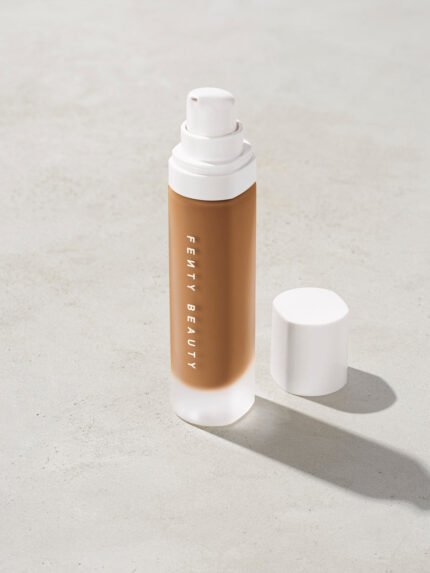 open bottle of Fenty Beauty Pro Filt'r Soft Matte Longwear Foundation with pump dispenser in shade 385 on concrete background