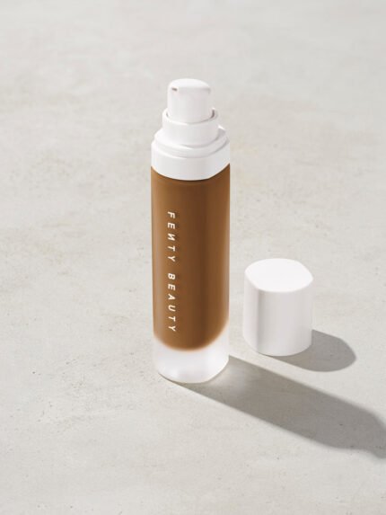 open bottle of Fenty Beauty Pro Filt'r Soft Matte Longwear Foundation with pump dispenser in shade 445 on concrete background