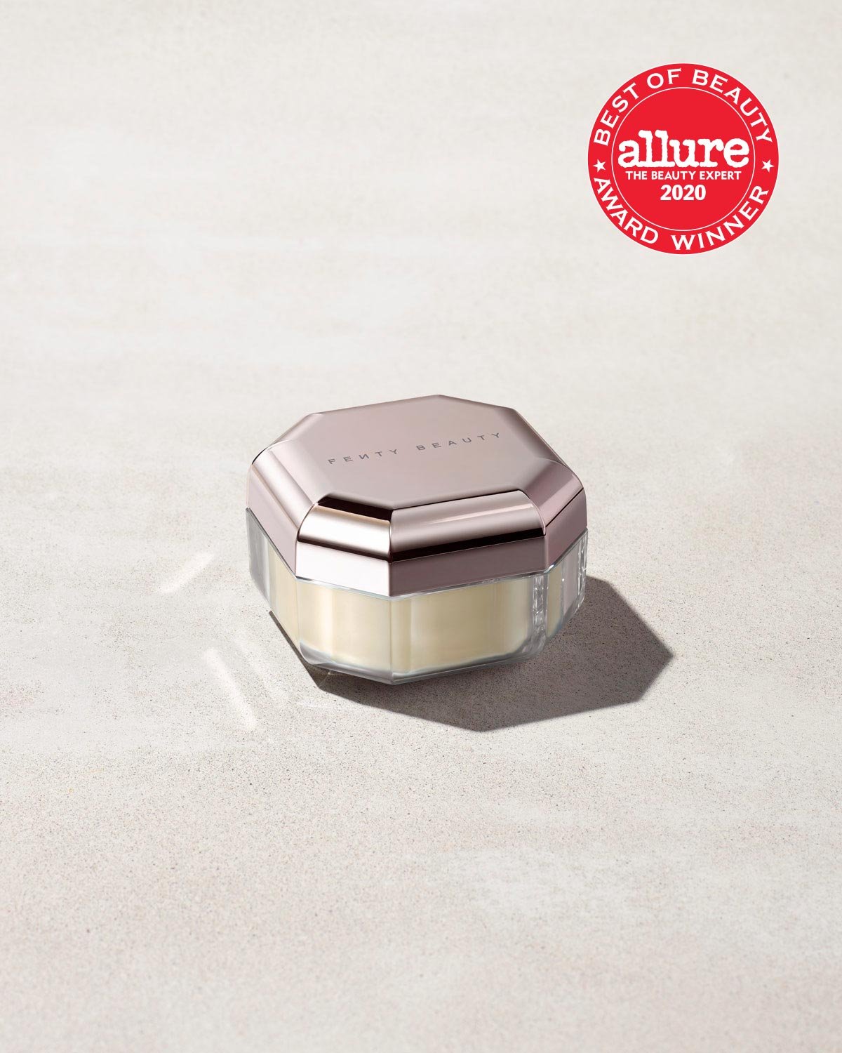 44764_SettingPowder_Concrete_CLOSED_1200x1500_RGB_BUTTER_FENTYVERSE Closed container of Pro Filt'r Instant Retouch Setting Powder in shade butter on a concrete background. Allure best of beauty award winner 2020 badge on the top right.