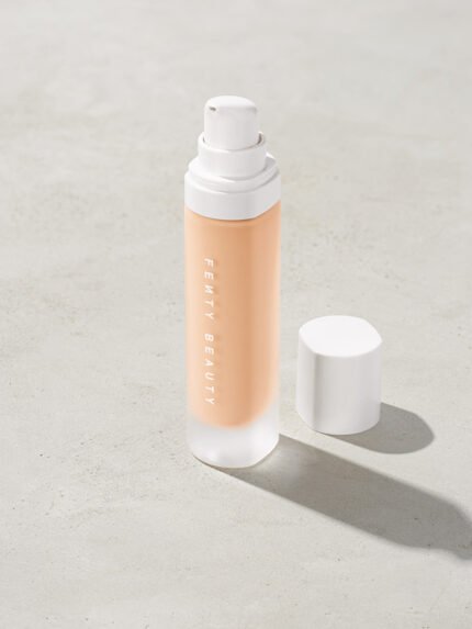 open bottle of Fenty Beauty Pro Filt'r Soft Matte Longwear Foundation with pump dispenser in shade #100 on concrete background