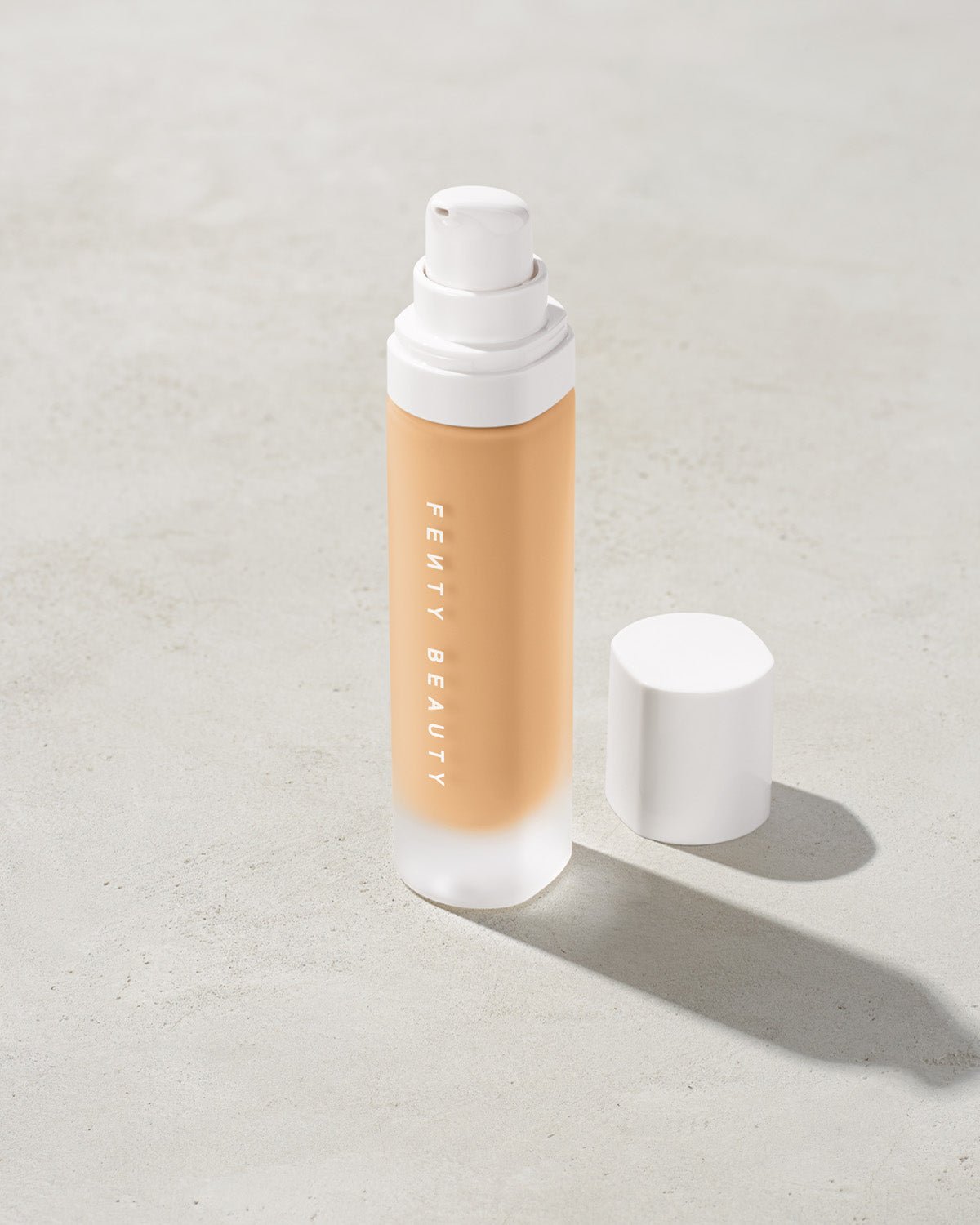 FB30006_FB0190_alt1 open bottle of Fenty Beauty Pro Filt'r Soft Matte Longwear Foundation with pump dispenser in shade #190 on concrete background