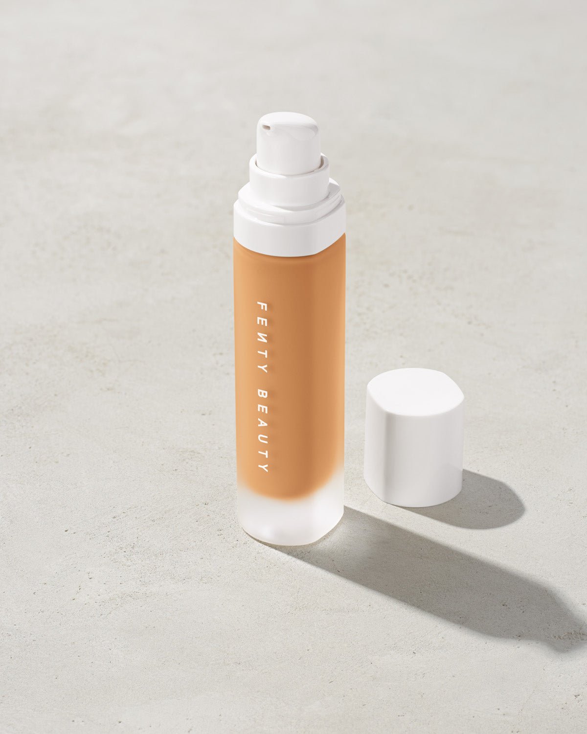 FB30006_FB0280_alt1 open bottle of Fenty Beauty Pro Filt'r Soft Matte Longwear Foundation with pump dispenser in shade #280 on concrete background