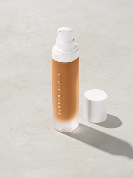 open bottle of Fenty Beauty Pro Filt'r Soft Matte Longwear Foundation with pump dispenser in shade 390 on concrete background
