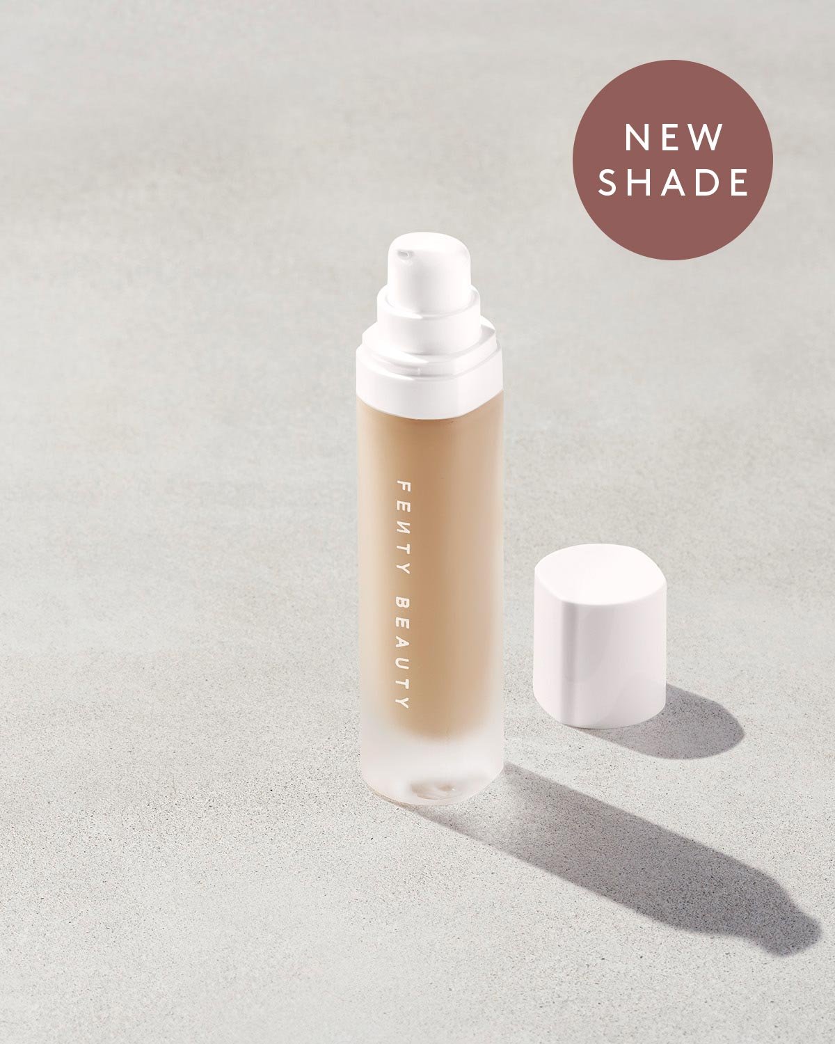 FB_FAL22_T2PRODUCT_CONCRETE_PRO_FILT_R_SOFT_MATTE_FOUNDATION_OPEN_225_1200x1500_FENTYVERSE open bottle of Fenty Beauty Pro Filt'r Soft Matte Longwear Foundation with pump dispenser in shade #225 on concrete background