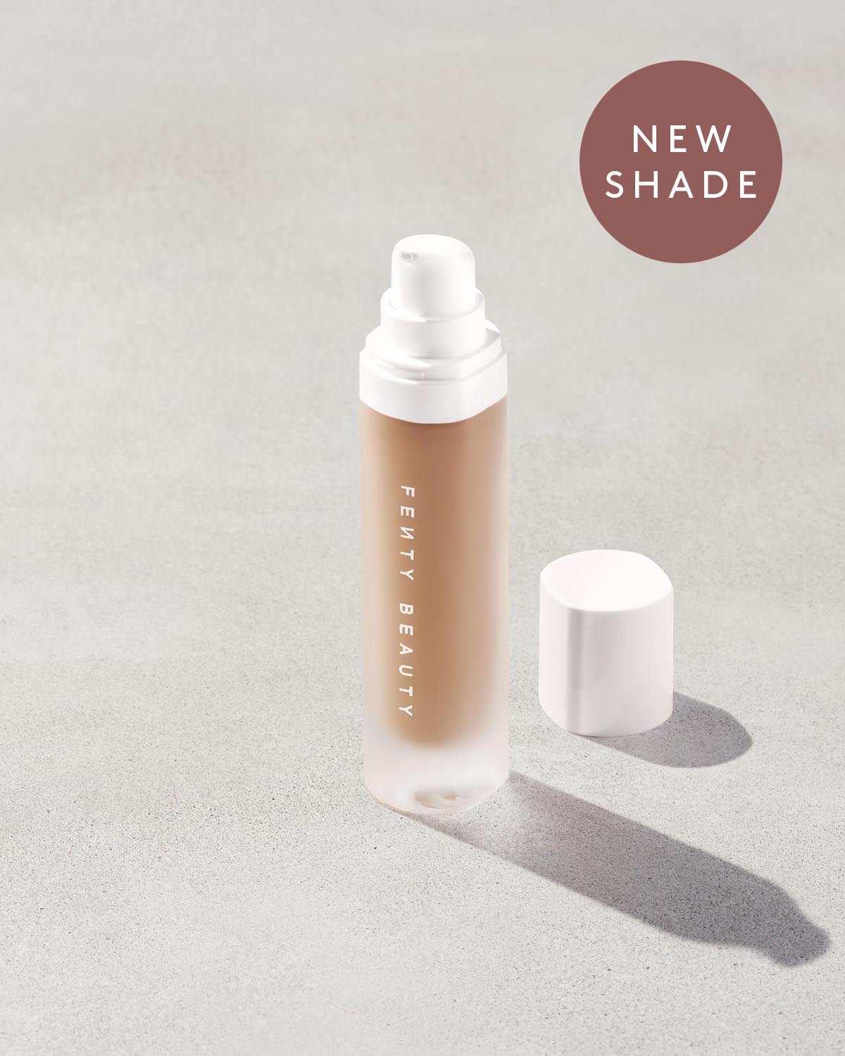 FB_FAL22_T2PRODUCT_CONCRETE_PRO_FILT_R_SOFT_MATTE_FOUNDATION_OPEN_295_1200x1500_FENTYVERSE Open bottle of a new shade of Fenty Beauty Pro Filt'r Soft Matte Longwear Foundation with pump dispenser in shade #295 on concrete background