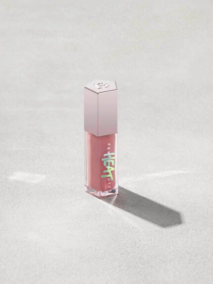 tube of Fenty Beauty Gloss Bomb Heat Universal Lip Luminizer + Plumper in shade Fussy Heat on concrete background