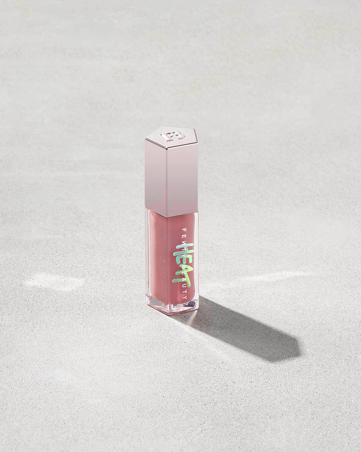 FB_HOL2021_I_T2PRODUCT_CONCRETE_GLOSS_BOMB_HEAT_CLOSED_FUSSY_1200x1500_af09fa25-f6cd-4182-8200-b4b4a01881d5 tube of Fenty Beauty Gloss Bomb Heat Universal Lip Luminizer + Plumper in shade Fussy Heat on concrete background
