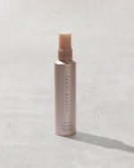 You Mist Makeup-Extending Setting Spray bottle on a concrete backdrop.