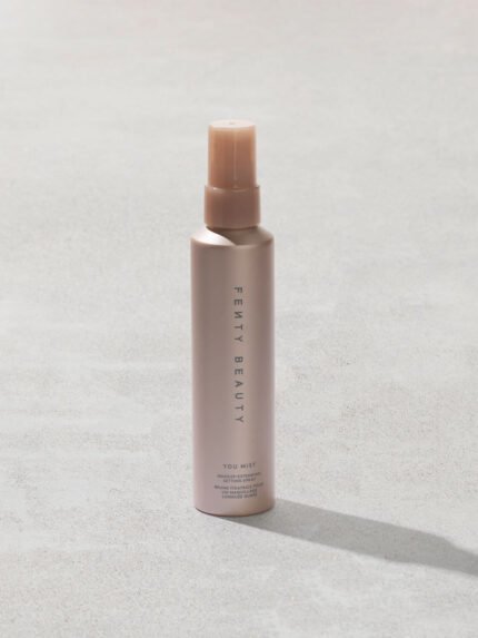 You Mist Makeup-Extending Setting Spray bottle on a concrete backdrop.