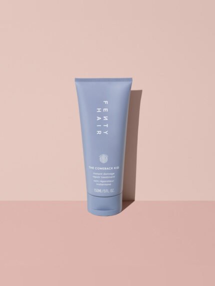 Fenty Hair The Comeback Kid Instant Damage Repair Hair Treatment Bond Builder tube made of 50% post-consumer recycled plastic on a pink background.