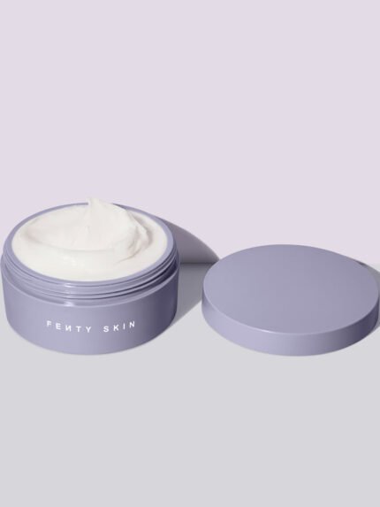 An open tub of Butta Drop Whipped Oil Body Cream with Tropical Oils + Shea Butter on a lilac background.